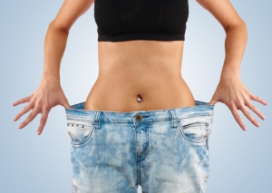 Beautiful young woman with big jeans, isolated on white.Woman showing how much weight she lost. Healthy lifestyles concept.