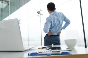 Stressed business man stretching in his office.