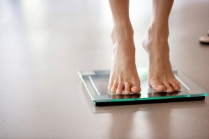 Legs of a woman standing on a weight scale, selective focus