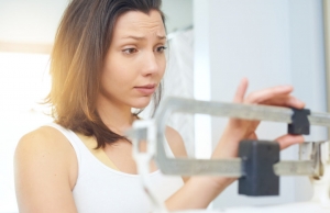 Shot of a young woman weighing herself on a scale